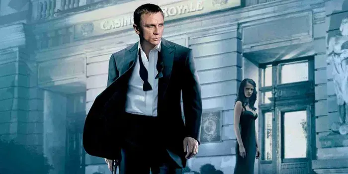 James Bond incarné par Daniel Craig en smoking devant le Casino Royale, une femme en robe noire en retrait dans l'ombre